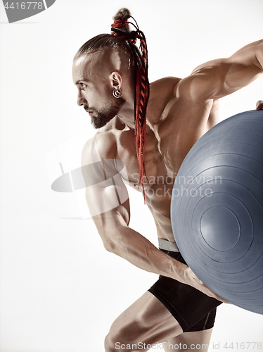 Image of Muscular man holding fitness ball, standing isolated on white