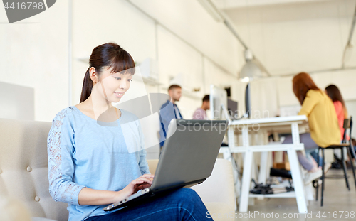 Image of happy asian woman with laptop working at office