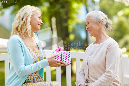 Image of daughter giving present to senior mother at park