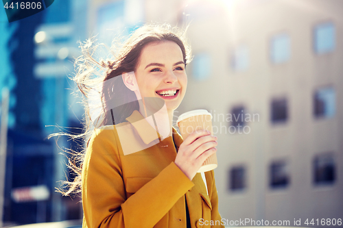 Image of happy young woman drinking coffee on city street