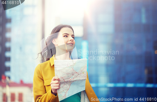 Image of happy young woman traveling with map in city