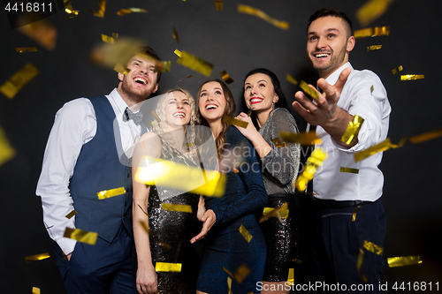 Image of happy friends at party under confetti over black