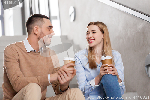 Image of man and woman with coffee talking at office stairs