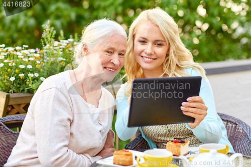 Image of daughter with tablet pc and senior mother at cafe