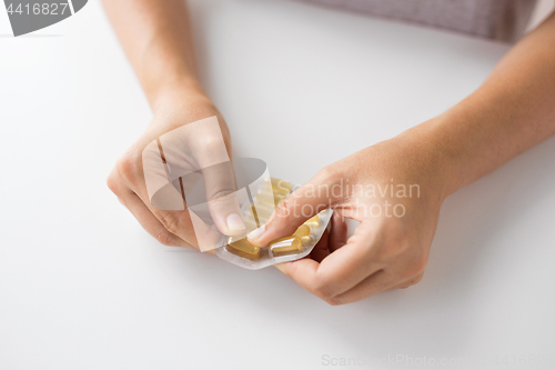 Image of woman hands opening pack of medicine capsules