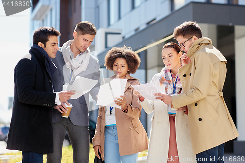 Image of international business team with papers outdoors