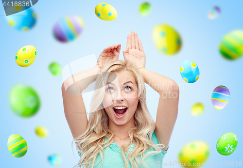 Image of happy woman making bunny ears over easter eggs