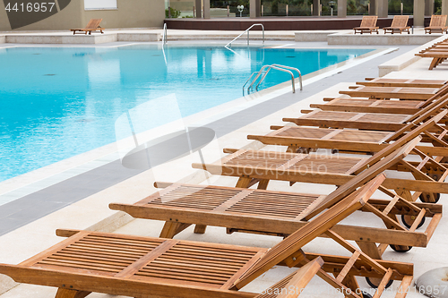 Image of Luxury swimming pool with wooden deck chairs.