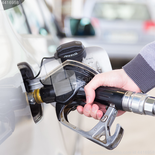 Image of Closeup of mans hand pumping gasoline fuel in car at gas station.