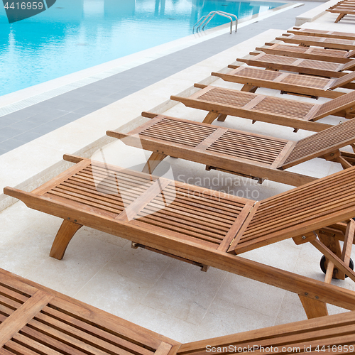 Image of Luxury swimming pool with wooden deck chairs.