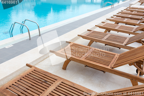 Image of Luxury swimming pool with wooden deck chairs.