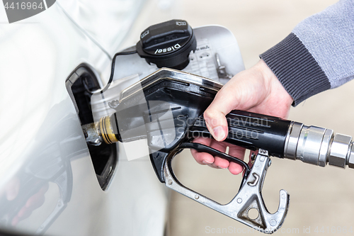 Image of Closeup of mans hand pumping gasoline fuel in car at gas station.