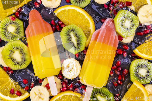 Image of Fruit ice cream on stick with slices fruits on black