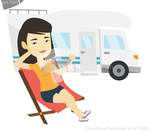 Image of Woman sitting in chair in front of camper van.