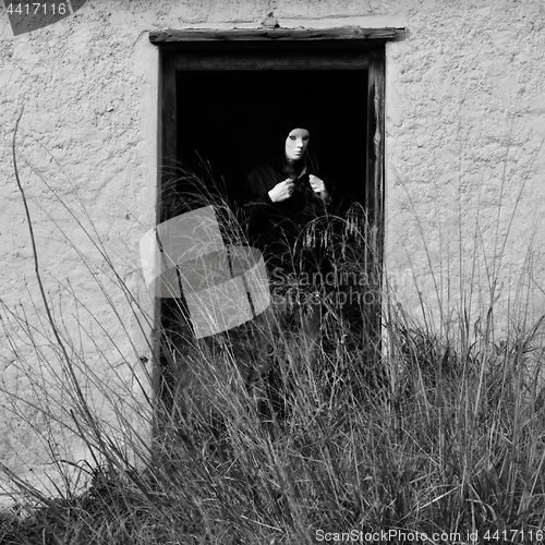 Image of masked figure by broken door