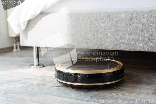 Image of Robot vacuum cleaner runs under bed