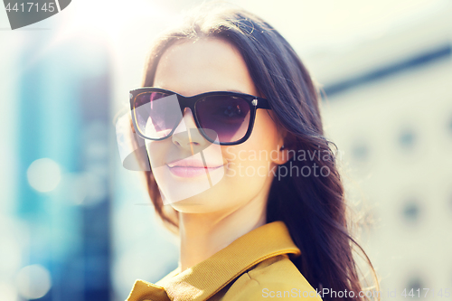 Image of smiling young woman with sunglasses in city