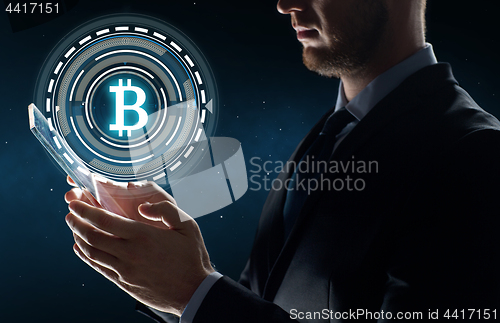 Image of businessman with tablet pc and bitcoin hologram