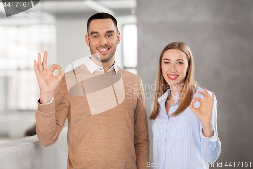 Image of businesswoman and businessman showing ok at office