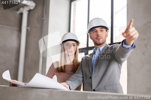 Image of architects with blueprint and helmets at office