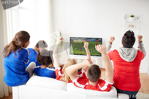 Image of football fans watching soccer game on tv at home