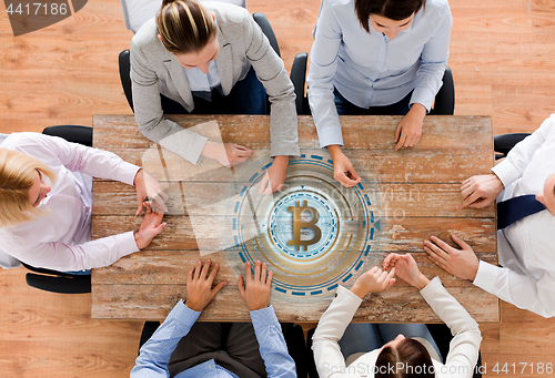 Image of business team at table with bitcoin icon