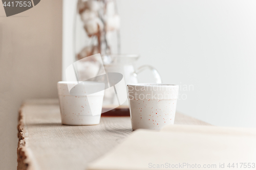 Image of Cup of coffee, branch of tree, wooden windowsill