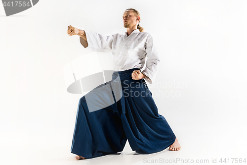 Image of Aikido master practices defense posture. Healthy lifestyle and sports concept. Man with beard in white kimono on white background.