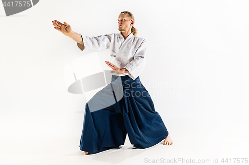 Image of Aikido master practices defense posture. Healthy lifestyle and sports concept. Man with beard in white kimono on white background.