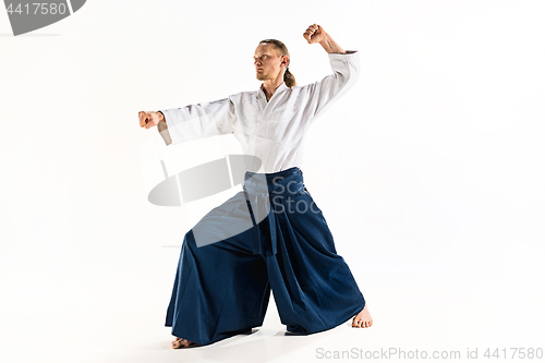 Image of Aikido master practices defense posture. Healthy lifestyle and sports concept. Man with beard in white kimono on white background.