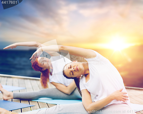 Image of women doing yoga exercises outdoors