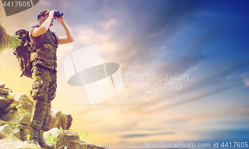 Image of soldier with backpack looking to binocular