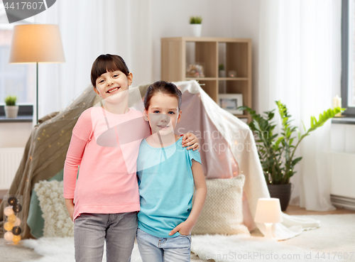 Image of happy smiling little girls hugging at home