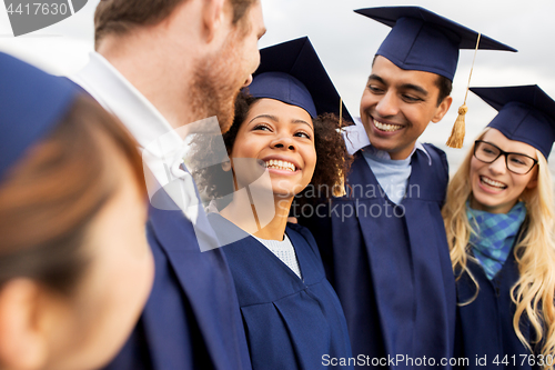 Image of happy students or bachelors in mortar boards