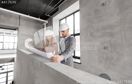 Image of architects with blueprint and helmets at office