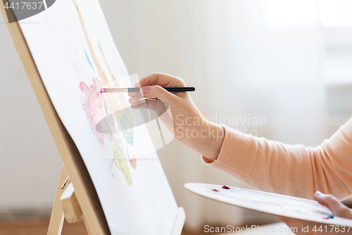 Image of artist with palette and brush painting at studio