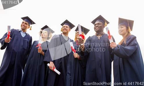 Image of happy students in mortar boards with diplomas