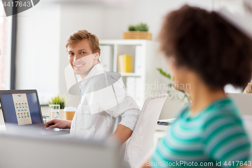 Image of happy creative workers with laptops at office