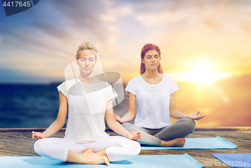 Image of women meditating in yoga lotus pose outdoors