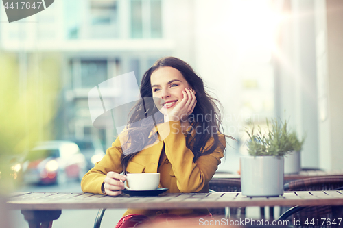 Image of happy woman drinking cocoa at city street cafe