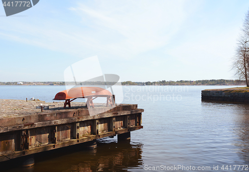 Image of Upturned red boat on a jetty above the sea