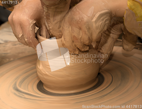 Image of Beginner and teacher in process of making clay bowl on pottery w