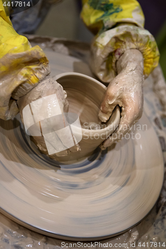 Image of Hands of young girl in process of making crockery on pottery whe