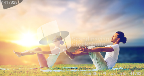 Image of couple making yoga half-boat pose outdoors