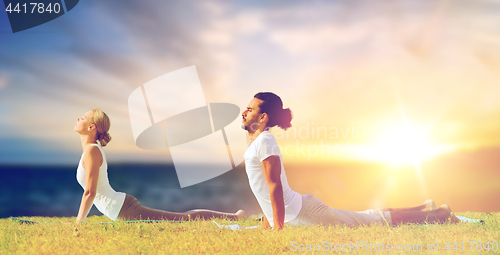 Image of couple making yoga cobra pose outdoors