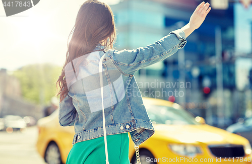 Image of young woman or girl catching taxi on city street