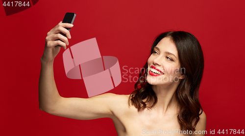 Image of beautiful woman taking selfie with smartphone