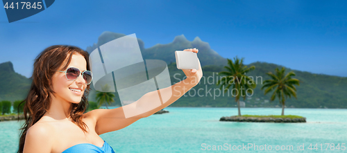 Image of woman taking selfie by smartphone on bora bora