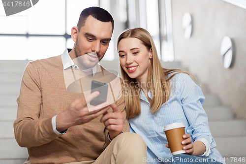 Image of man and woman with smartphone at office stairs