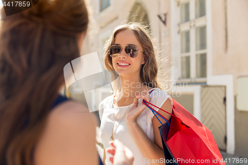 Image of happy women with shopping bags at storefront